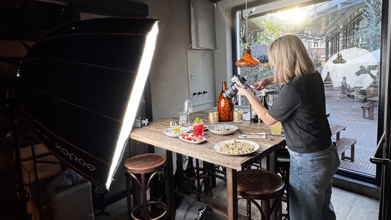 Pien styling a table of dishes on a lit set